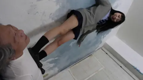 Older Asian guy jerking off while slim tattooed woman stands over him